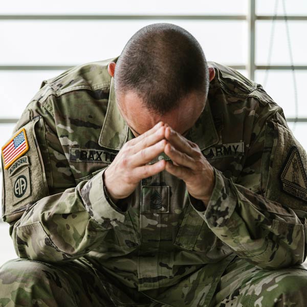 Man in U.S. Army fatigues sitting with head in hands